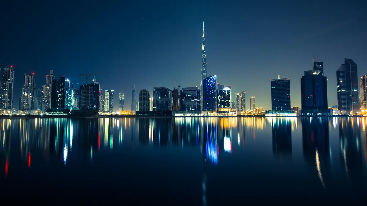 The Dubai skyline reflected in still water at night