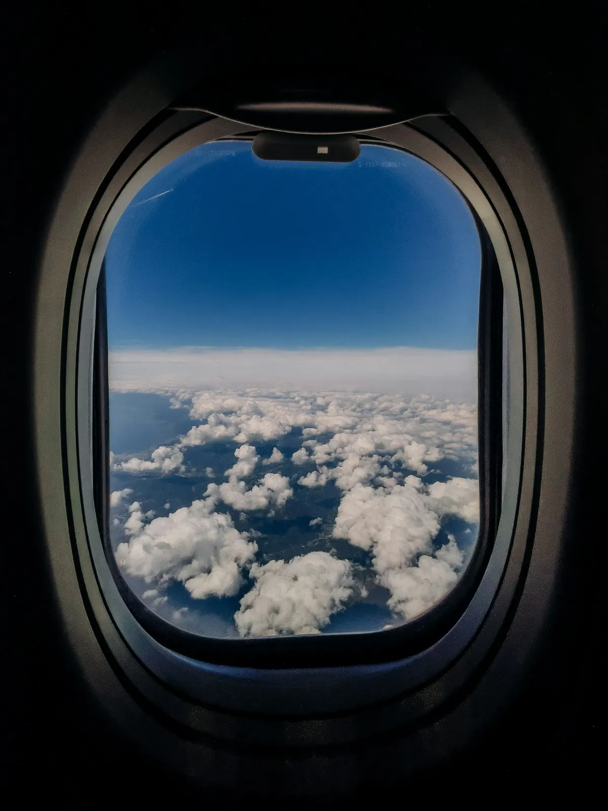 Looking out of an aircraft window at clouds far below